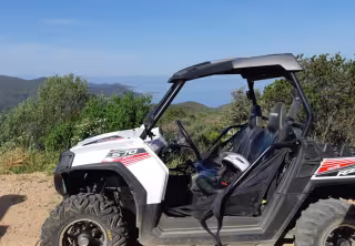 Buggy tout-terrain arrêté sur un chemin dans le maquis, la mer au loin