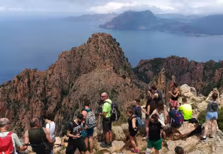 Groupe de randonneurs au sommet d'un piton rocheux dominant la mer