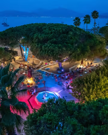 Le village illuminé en soirée, avec la mer et les lumières du golfe au fond