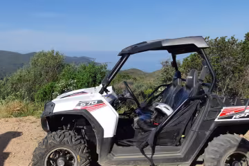 Buggy tout-terrain arrêté sur un chemin dans le maquis, la mer au loin