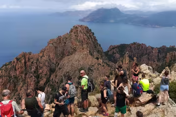 Groupe de randonneurs au sommet d'un piton rocheux dominant la mer